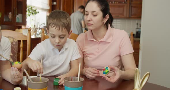 Mom Helps Her Sons Paint Easter Eggs