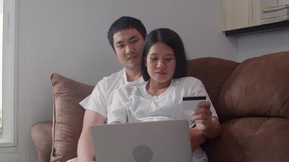 Young Asian Pregnant couple online shopping using laptop and credit card buying baby product.