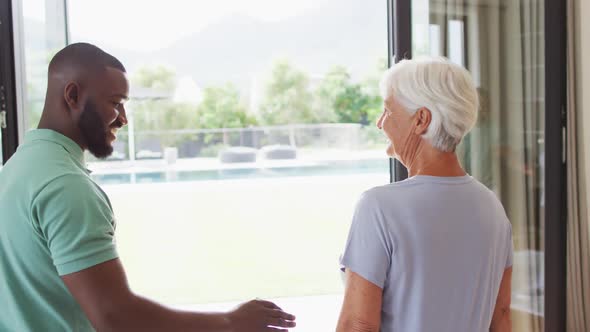 Video of happy african american male physiotherapist exercising with caucasian senior woman