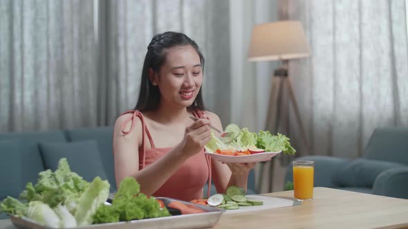 Smiling Asian Woman Enjoys Eating Healthy Food At Home