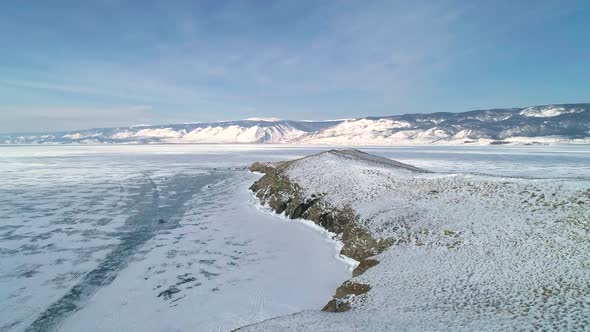 Aerial Over the Lands of Rocky Snow Covered Island in Lake Baikal Surrounded with Ice