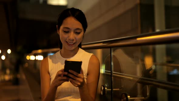 Young Woman using smart phone in city at night 