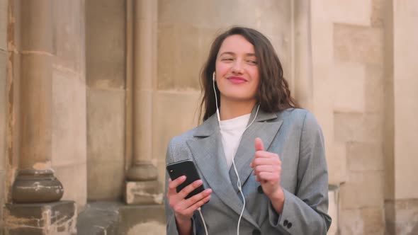 Woman in Headphones Earphones Listening to Music in the Street and Dancing