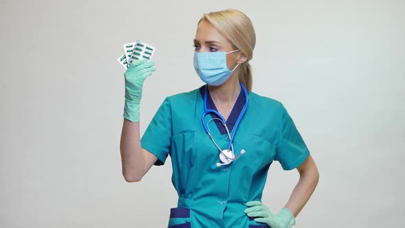 Medical Doctor Nurse Woman Wearing Protective Mask and Rubber or Latex Gloves - Holding Pills