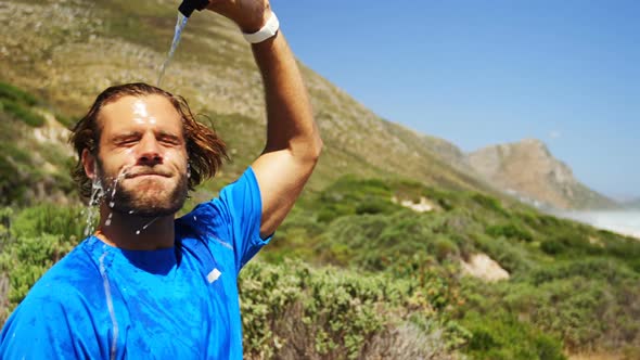 Triathlete man pouring water on his face on a sunny day