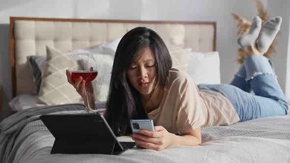 Serious Woman in Casual Clothes Talking on Video Call on Digital Tablet Lying on the Bed