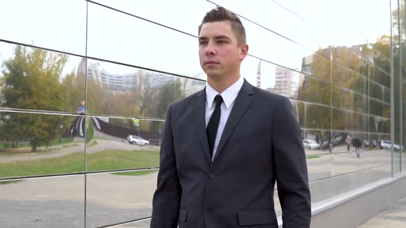 A Young Businessman in a Suit Walks Along a Business Center, A Serious Man, Mirrored Business Center