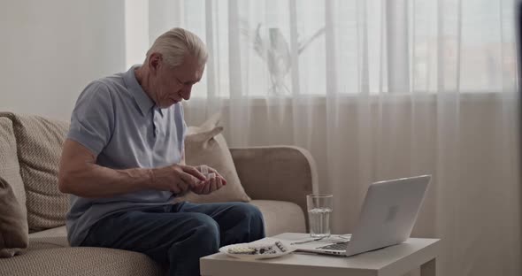 Aged Man Taking Pills in Living Room