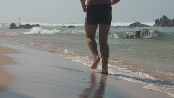 Energetic Man Spends Leisure Time Jogging Along Yellow Beach