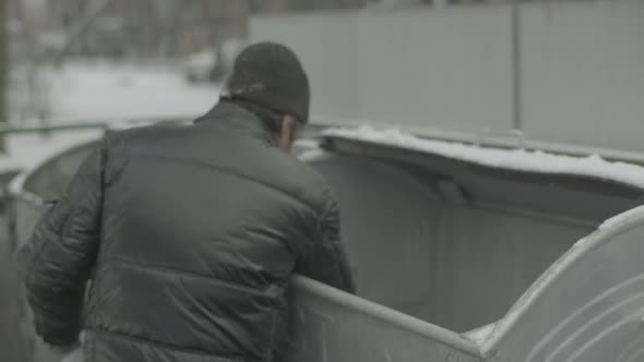 A Beggar Homeless Man Tramp Is Looking for Food in a Trash Can. Kyiv. Ukraine