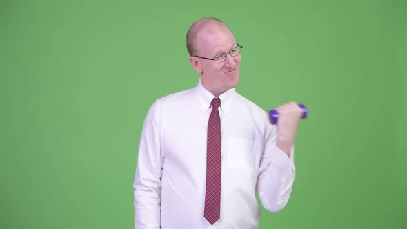 Mature Bald Businessman Exercising with Dumbbells