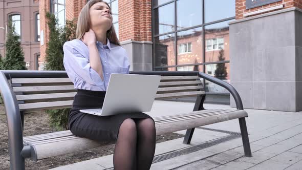 Tired Young Woman Sitting Outside Office Working on Laptop