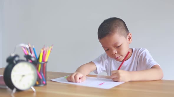 boy sitting and doing homework, drawing, coloring