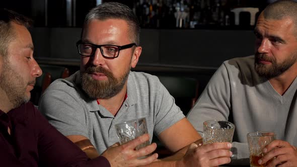 Group of Mature Male Friends Laughing and Talking Over Glass of Whiskey at the Bar