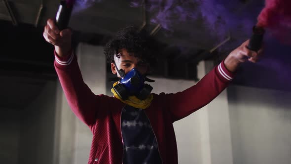 Mixed race man holding blue and purple flares standing in an empty building