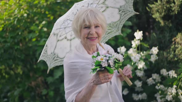 Elegant Senior Bride with Bouquet and Sun Umbrella Posing in Slow Motion on Sunny Spring Summer Day