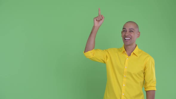 Happy Handsome Bald Businessman Pointing Up and Looking Surprised