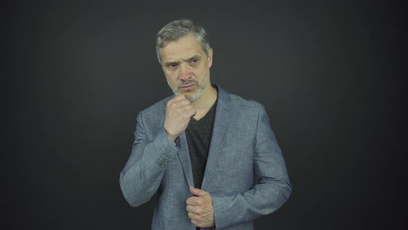 Serious Man in Blue Classic Suit Runs Hand on Grey Beard