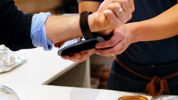 Hand of customer making payment through smartwatch