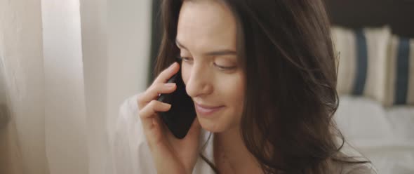 Close up of a woman in white shirt talking to someone on the phone and smiling, 
