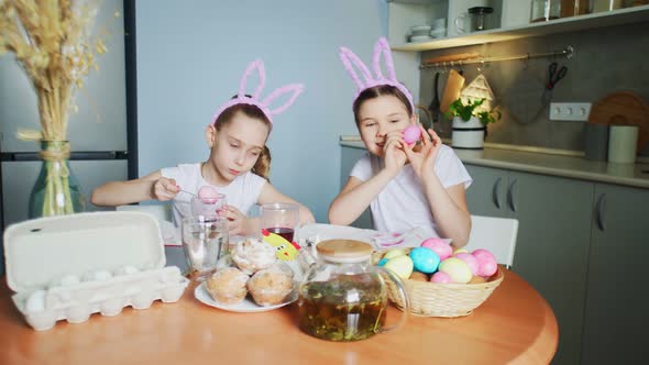 Funny Little Sisters Wearing Bunny Ears Painting Eggs on Easter Day