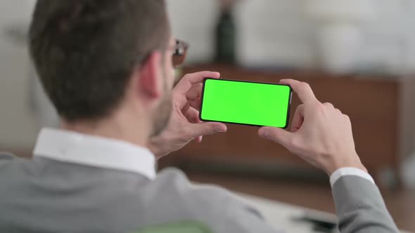 Rear View of Man Watching Smartphone with Chroma Key Screen