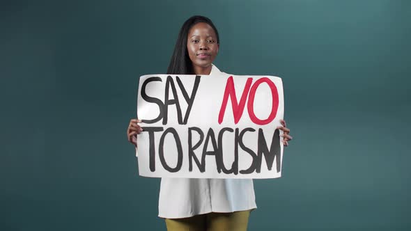 A Beautiful African Girl is Proudly Showing a Poster Against Racism and Walking Away