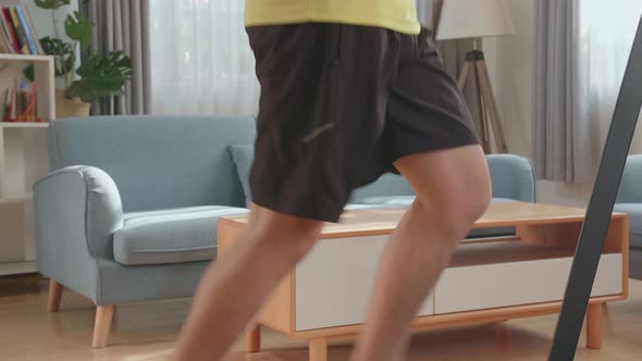 Side View Of Asian Man Running On A Treadmill At Home