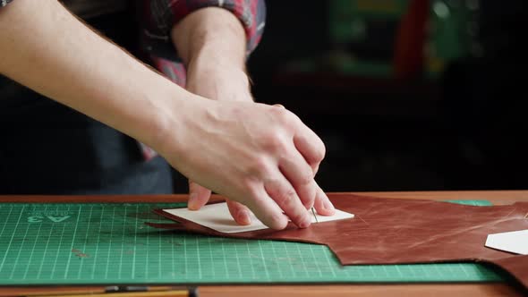 Man Tailor Cutting Artificial Leather with Stencil Closeup