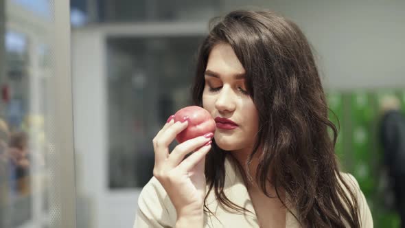 Portrait of Stylish Lady Determines the Quality of a Peach in a Supermarket