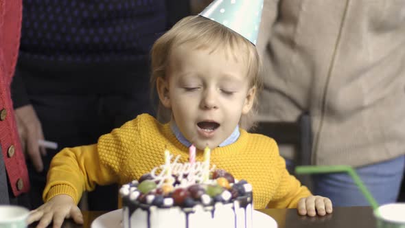 Toddler Boy Blows Candles on His Birthday at Home
