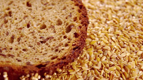 Whole grain rye slice of dark bread in a pile of flaxseeds. Grain fiber healthy farm food