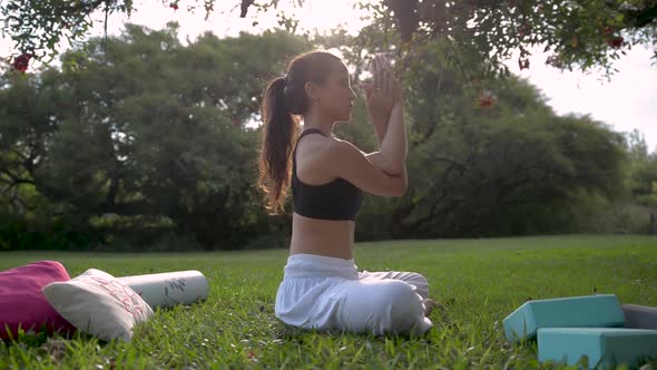 Side View of Young Woman Practicing Yoga Sitting Under a Tree.Wellness Concept