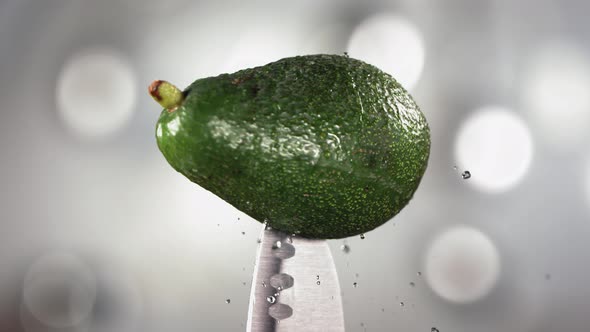 Fresh Avocado Falling Down with Drop on Knife Stuck