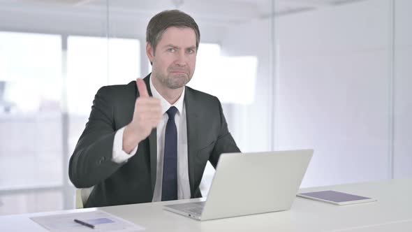 Ambitious Middle Aged Businessman Doing Thumbs Up in Office 