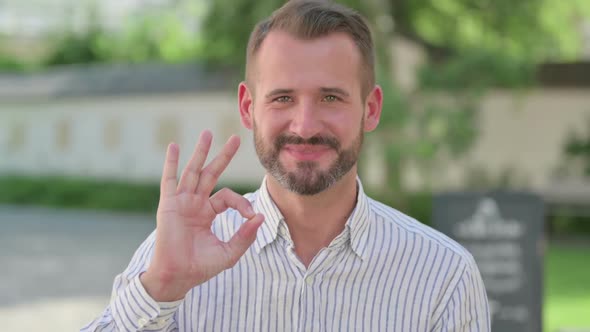 Outdoor Portrait of Middle Aged Man Showing Ok Sign