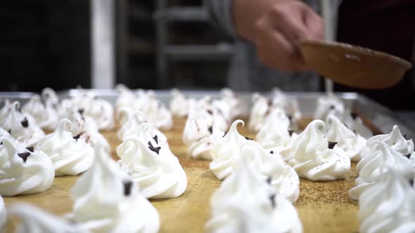 Human Hand Holding Utensil with Cocoa Flour on to Slowly Decorate White Whisked Pastry in Kitchen