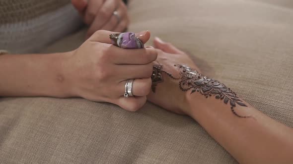 Close Up Shot of a Woman's Hands, Who Draws a Floral Henna Pattern for a Friend