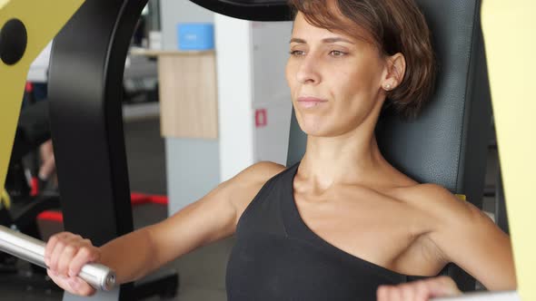 Sporty Woman is Making Exercises for Arms Muscles on Training Machine