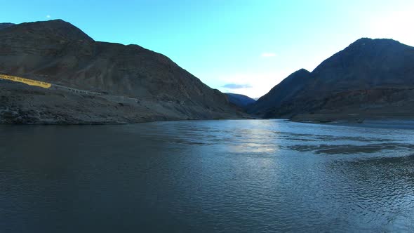 the confluence and convergence of river zanskar and indus with mountains and sun in the background f