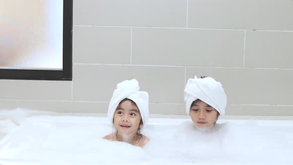 two daughters with bubbles in bathtub