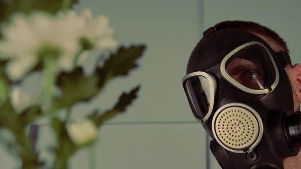 Man in a Gas Mask Looking at Flowers