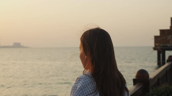 Attractive Woman Looking at City Skyline Across the Ocean