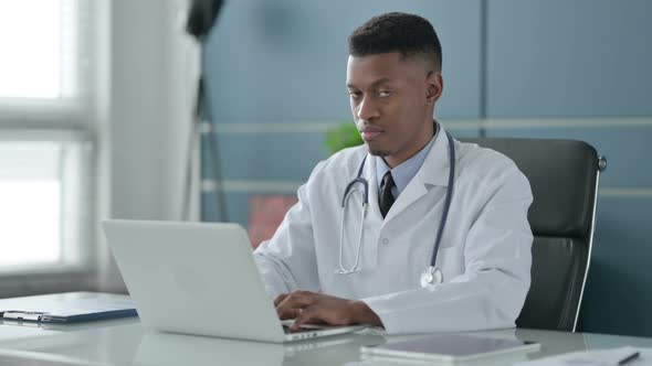 African Doctor Shaking Head as No Sign while using Laptop in Office