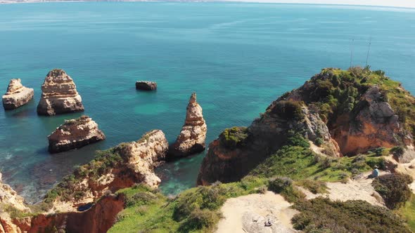 Sandstone cliffs shrouded in lush green grass encircled by Algarve Idyllic sea