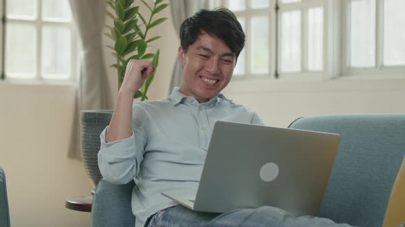 Male Use Laptop Computer And Celebrating In Living Room