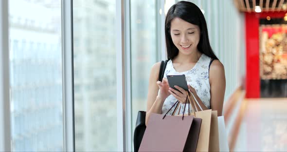 Woman working on cellphone and holding shopping bags 