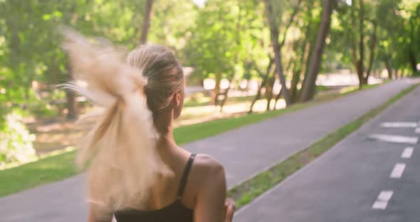 Active Blonde Girl Jogging on Special Training Path in Public Park Early in Morning