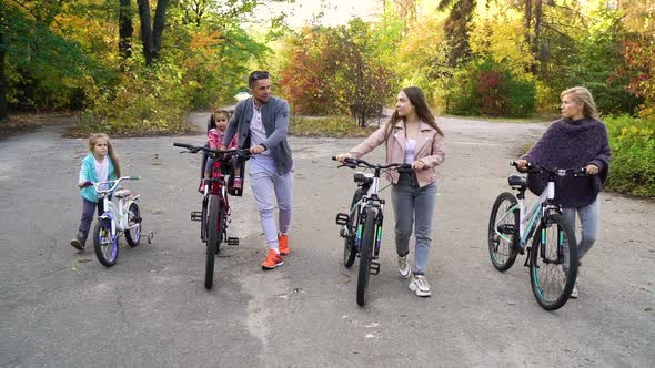 Family of five walking with bicycles in autumn park