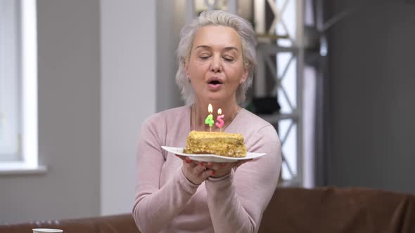 Portrait of Happy Confident Beautiful Caucasian Woman Blowing Out Candles on 45 Birthday Smiling